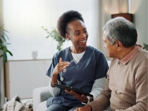 A picture of a female healthcare worker showing a male patient on an electronic device.