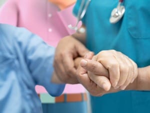 A picture of a patient holding hands with a person in the care sector.