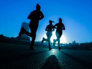 A picture of 3 people running in a sports environment.