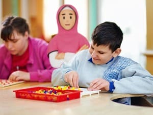 a picture of 2 children sat playing with a puzzle with a social care System C character.