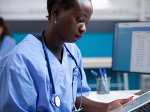 A picture of a female healthcare worker looking at an EPR system on an iPad.