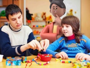 A picture of 2 children with making beads bracelets with a System C social care character.
