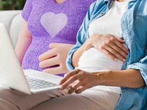 A picture of 2 pregant women looking at the BadgerNet EPAGU factsheet on a laptop device.