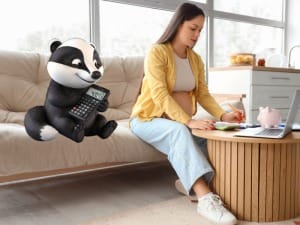 A picture of a pregnant women using our BadgerNet Maternity Benefits Calculator on a desktop, sat next to the System C BadgerNet character.