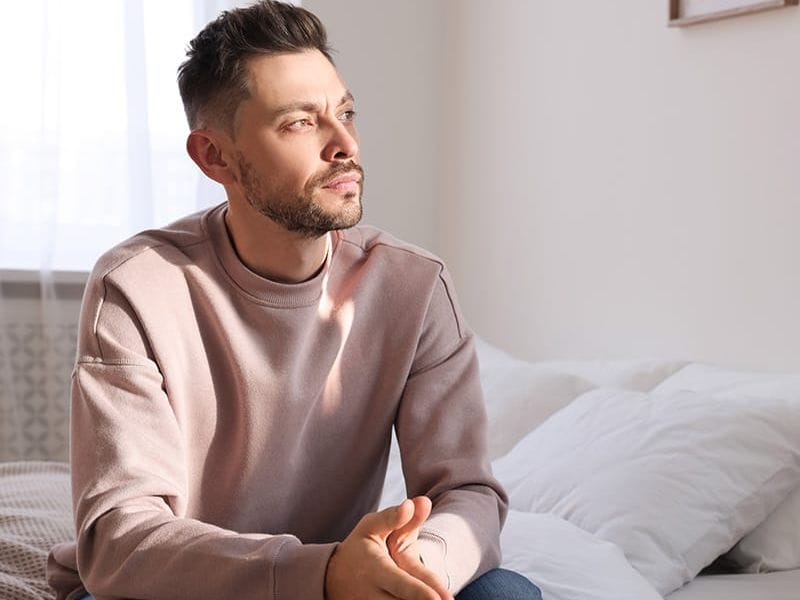 Man on a bed thinking